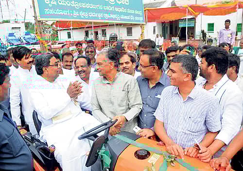 ಕೃಷಿ ಯಂತ್ರಧಾರೆ ಯೋಜನೆಯಡಿ ನೀಡುವ ಯಂತ್ರೋಪಕರಣಗಳ ಬಾಡಿಗೆ ಕೇಂದ್ರವನ್ನು ಧಾರವಾಡ ಜಿಲ್ಲೆ ಕುಂದಗೋಳ ತಾಲ್ಲೂಕು ಸಂಶಿಯಲ್ಲಿ ಸೋಮವಾರ ಉದ್ಘಾಟಿಸಿದ ಮುಖ್ಯಮಂತ್ರಿ ಸಿದ್ದರಾಮಯ್ಯ ಟ್ರ್ಯಾಕ್ಟರ್ ಮೇಲೆ ಕುಳಿತು ನಗೆ ಬೀರಿದ ಕ್ಷಣ. ಶಾಸಕರಾದ ಎನ್.ಎಚ್.ಕೋನರಡ್ಡಿ, ಸಿ.ಎಸ್.ಶಿವಳ್ಳಿ, ಬಸವರಾಜ ಹೊರಟ್ಟಿ, ಸಚಿವರಾದ ದಿನೇಶ ಗುಂಡೂರಾವ್, ಕೃಷ್ಣ ಬೈರೇಗೌಡ ಹಾಗೂ ಶಾಸಕ ವಿನಯ ಕುಲಕರ್ಣಿ ಇದ್ದಾರೆ. ಪ್ರಜಾವಾಣಿ ಚಿತ್ರ