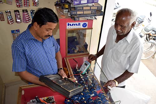 ಗ್ರಾಹಕರ ಎದುರು ವಾಲ್‌ಕ್ಲಾಕ್‌ನ ಬ್ಯಾಟರಿ ಚೆಕ್ ಮಾಡುವುದು.