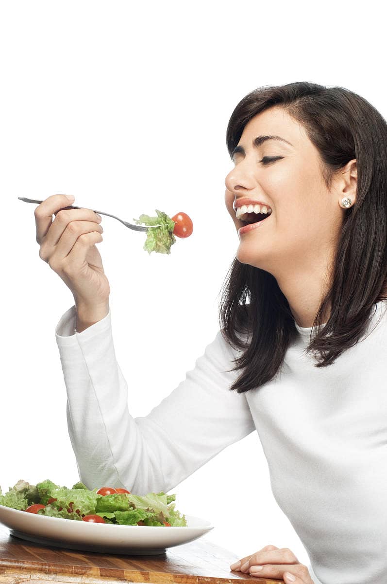 A woman eating salad. Isolated on white.A woman eating salad. Isolated on white.