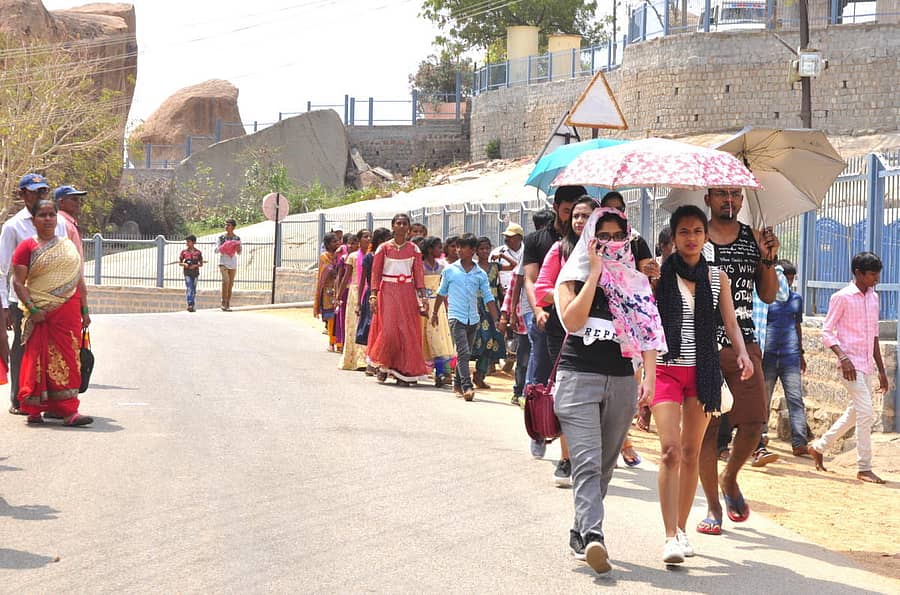 ಕೊಡೆಗಳನ್ನು ಹಿಡಿದುಕೊಂಡು ಹಂಪಿ ಉತ್ಸವದಲ್ಲಿ ಭಾಗಿಯಾದ ಪ್ರವಾಸಿಗರು – ಪ್ರಜಾವಾಣಿ ಚಿತ್ರ: ಬಿ. ಬಾಬುಕುಮಾರ