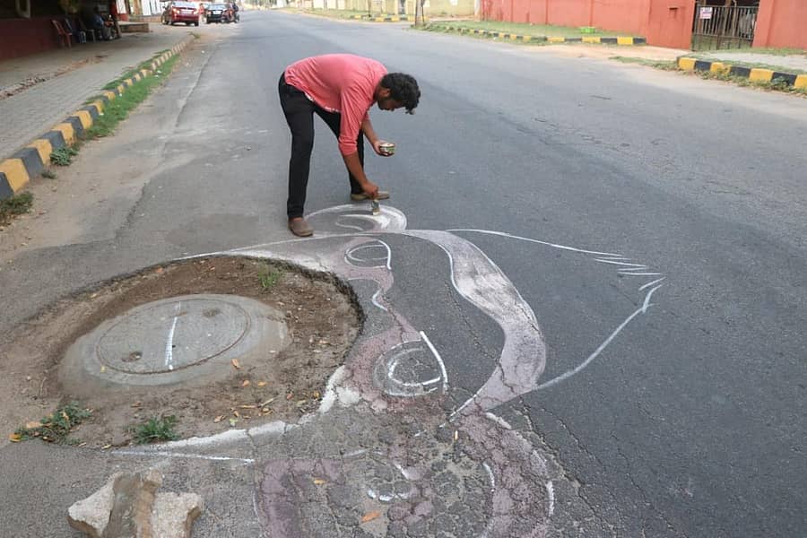 ಮೈಸೂರಿನ ಚಾಮುಂಡಿ ವಿಹಾರ ಕ್ರೀಡಾಂಗಣ ಬಳಿಯ ಮ್ಯಾನ್ ಹೋಲ್ ಸುತ್ತಲೂ ಚಿತ್ರ ಬಿಡಿಸುತ್ತಿರುವ ಕಲಾವಿದ ಶಿವರಂಜನ್