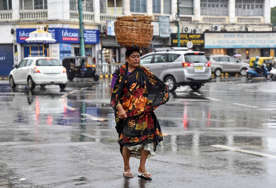 ಮೈಸೂರಿನಲ್ಲಿ ಶುಕ್ರವಾರ ಸಂಜೆ ಸುರಿದ ಜಿಟಿಜಿಟಿ ಮಳೆಯಲ್ಲಿ ತೋಯ್ಯುತ್ತಲೇ ವ್ಯಾಪಾರಿ ಮಹಿಳೆಯೊಬ್ಬರು ಸಾಗಿದ ದೃಶ್ಯ ಕೆ.ಆರ್.ವೃತ್ತದಲ್ಲಿ ಕ್ಯಾಮೆರಾ ಕಣ್ಣಿಗೆ ಸೆರೆಯಾಯಿತು- ಚಿತ್ರ ಬಿ.ಆರ್.ಸವಿತಾ