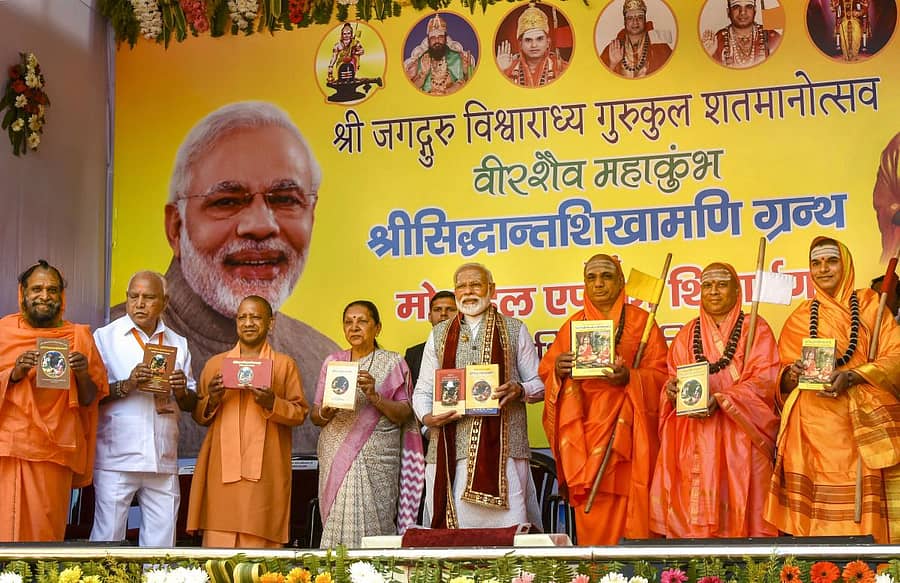 19 ಭಾಷೆಗಳಿಗೆ ತರ್ಜುಮೆಯಾದ ಸಿದ್ಧಾಂತ ಶಿಖಾಮಣಿ ಗ್ರಂಥಗಳ ಬಿಡುಗಡೆ ಕಾರ್ಯಕ್ರಮದಲ್ಲಿ ಮುಖ್ಯಮಂತ್ರಿ ಬಿ.ಎಸ್. ಯಡಿಯೂರಪ್ಪ, ಉತ್ತರ ಪ್ರದೇಶ ಮುಖ್ಯಮಂತ್ರಿ ಯೋಗಿ ಆದಿತ್ಯನಾಥ್, ರಾಜ್ಯಪಾಲರಾದ ಆನಂದಿ ಬೇನ್, ಪ್ರಧಾನಿ ನರೇಂದ್ರ ಮೋದಿ, ಕಾಶಿ ಪೀಠದ ಡಾ. ಚಂದ್ರಶೇಖರ ಶಿವಾಚಾರ್ಯ ಶ್ರೀಗಳು, ಚನ್ನಸಿದ್ದರಾಮ ಪಂಡಿತಾರಾಧ್ಯ ಶಿವಾಚಾರ್ಯ ಸ್ವಾಮೀಜಿ ಇದ್ದರು – ಪಿಟಿಐ ಚಿತ್ರ