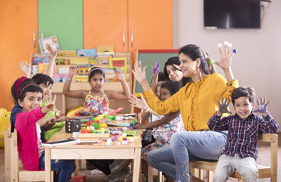 Teacher with preschool students having fun while finger painting at classTeacher with preschoolers finger painting at class