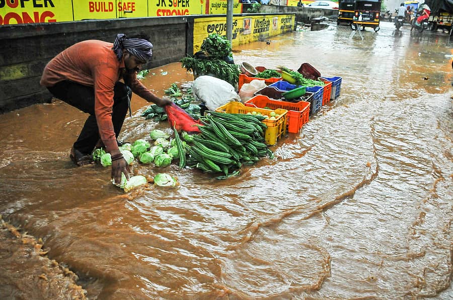 ಹುಬ್ಬಳ್ಳಿಯ ಸವಾಯಿ ಗಂಧರ್ವ ಹಾಲ್ ಬಳಿ ಸೋಮವಾರ ಸುರಿದ ಭಾರಿ ಮಳೆಗೆ ತರಕಾರಿಗಳು ನೀರಿನಲ್ಲಿ ಕೊಚ್ಚಿ ಹೋಗುವುದನ್ನು ತಡೆಯುತ್ತಿರುವ ವ್ಯಾಪಾರಿ
