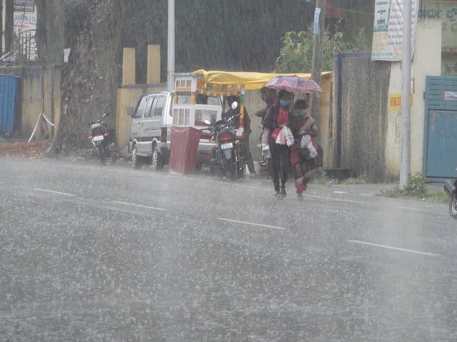 ಹಾಸನದಲ್ಲಿ ಮಳೆ ಸುರಿದ ವೇಳೆ ಕೊಡೆ ಹಿಡಿದು ಸಾಗಿದ ಮಹಿಳೆಯರು.