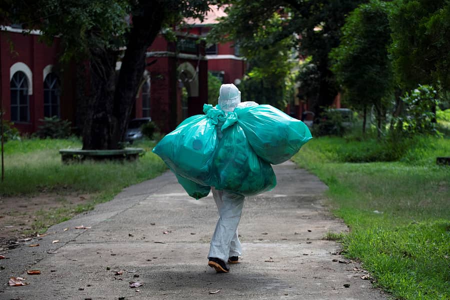 ವೈಯಕ್ತಿಕ ರಕ್ಷಣಾ ಕವಚ ಧರಿಸಿರುವ ಆರೋಗ್ಯ ಕಾರ್ಯಕರ್ತರೊಬ್ಬರು ಕೋವಿಡ್–ತ್ಯಾಜ್ಯವನ್ನು ವಿಲೇವಾರಿ ಮಾಡಲು ಹೊರಟಿರುವುದು (ರಾಯಿಟರ್ಸ್ ಚಿತ್ರ)