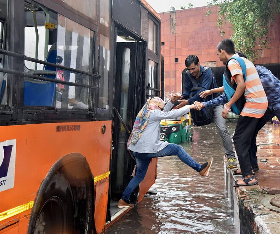 ದೆಹಲಿಯಲ್ಲಿ ಮಳೆಯಿಂದಾಗಿ ಬಸ್ನಿಂದ ಇಳಿಯಲೂ ಜನ ಹರಸಾಹಸಪಡುತ್ತಿರುವುದು (ಪಿಟಿಐ)