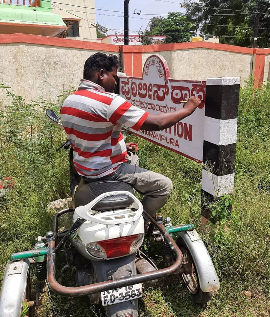 ವಾಹನದ ಮೇಲೆ ಕುಳಿತು ನಾಮಫಲಕ ಬರೆಯುತ್ತಿರುವ ಚಿತ್ರಕಲಾವಿದ ಅನಂತನಾಗ್