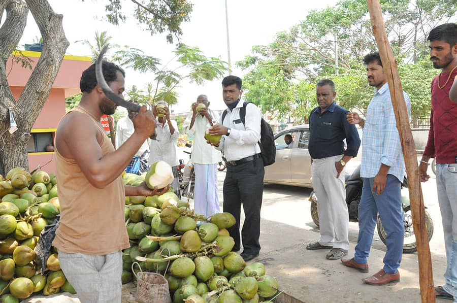 ಚಾಮರಾಜನಗರ ಡಿವೈಎಸ್‌ಪಿ ಕಚೇರಿ ಸಮೀಪ ವ್ಯಾಪಾರ ಮಾಡುತ್ತಿರುವ ಮಹೇಶ್‌ ಅವರ ಬಳಿ ಎಳನೀರಿಗಾಗಿ ಬಂದಿರುವ ಗ್ರಾಹಕರು