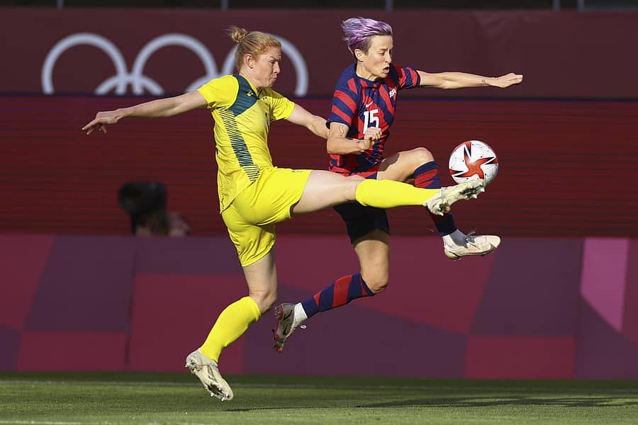 ಅಮೆರಿಕ ತಂಡದ ಮೇಗನ್ ರಾಪಿನೊ ಮತ್ತು ಆಸ್ಟ್ರೇಲಿಯಾದ ಕ್ಲೇರ್ ಪೊಲ್ಕಿಂಗೊರ್ನ್ (ಹಳದಿ ಪೋಷಾಕು) ಚೆಂಡಿನ ಮೇಲೆ ನಿಯಂತ್ರಣ ಸಾಧಿಸಲು ಪ್ರಯತ್ನಿಸಿದರು– ರಾಯಿಟರ್ಸ್ ಚಿತ್ರ