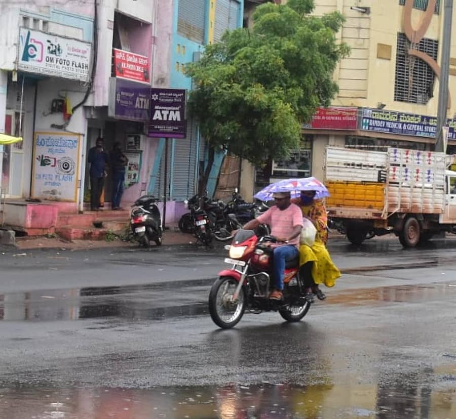ಹೊಸಪೇಟೆಯಲ್ಲಿ ಗುರುವಾರ ಸುರಿದ ಜಿಟಿಜಿಟಿ ಮಳೆಯಲ್ಲೇ ಬೈಕ್ ಸವಾರರು ಕೊಡೆ ಹಿಡಿದುಕೊಂಡು ಸಂಚರಿಸಿದರು