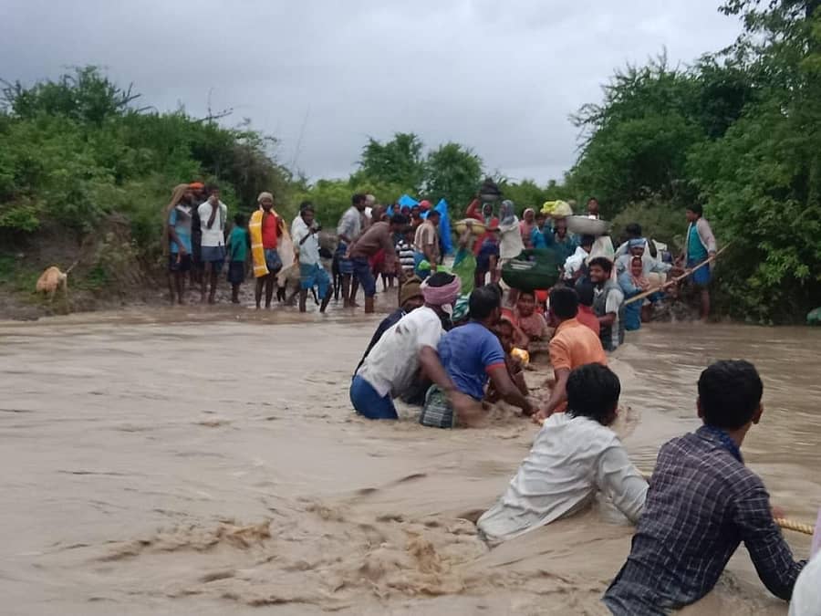 ಯಲಬುರ್ಗಾ ತಾಲ್ಲೂಕು ಬಂಡಿಹಾಳ ಗ್ರಾಮ ಹೊರವಲಯದಲ್ಲಿ ಹರಿಯುವ ಹಳ್ಳದಲ್ಲಿ ಕಾರ್ಮಿಕರು ಹಗ್ಗದ ಸಹಾಯದಿಂದ ದಡ ಸೇರಿದರು