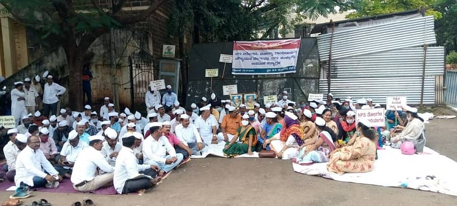 ಎನ್ಪಿಎಸ್ ರದ್ದುಪಡಿಸುವಂತೆ ಆಗ್ರಹಿಸಿ ಸರ್ಕಾರಿ ನೌಕರರು ಬೆಳಗಾವಿಯ ಜಿಲ್ಲಾಧಿಕಾರಿ ಕಚೇರಿ ಆವರಣದಲ್ಲಿ ಶನಿವಾರ ಪ್ರತಿಭಟನೆ ನಡೆಸಿದರು