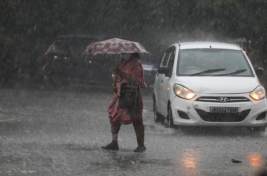 ಜಮ್ಮುವಿನಲ್ಲಿ ಸುರಿದ ಭಾರಿ ಮಳೆಯಲ್ಲಿ ಮಹಿಳೆಯೊಬ್ಬರು ಛತ್ರಿ ಹಿಡಿದು ರಸ್ತೆ ದಾಟಿದರು. ಪಿಟಿಐ ಚಿತ್ರ.