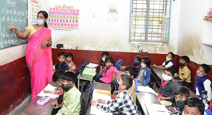 ಚಿತ್ರದುರ್ಗದ ಗುರುಕುಲ ಶಾಲೆಯ ಎಲ್ಕೆಜಿ ವಿಭಾಗದಲ್ಲಿ ಸೋಮವಾರ ಶಾಲೆಯ ಶಿಕ್ಷಕಿ ಕಾಗುಣಿತ ಹೇಳಿಕೊಡುತ್ತಿರುವುದು. ಮೊದಲ ದಿನ ಶಾಲೆಗೆ ಬಂದ ಚಿಣ್ಣರು ಮಾಸ್ಕ್ ಧರಿಸಿ ಪಾಠ ಕೇಳುತ್ತಿರುವುದು.