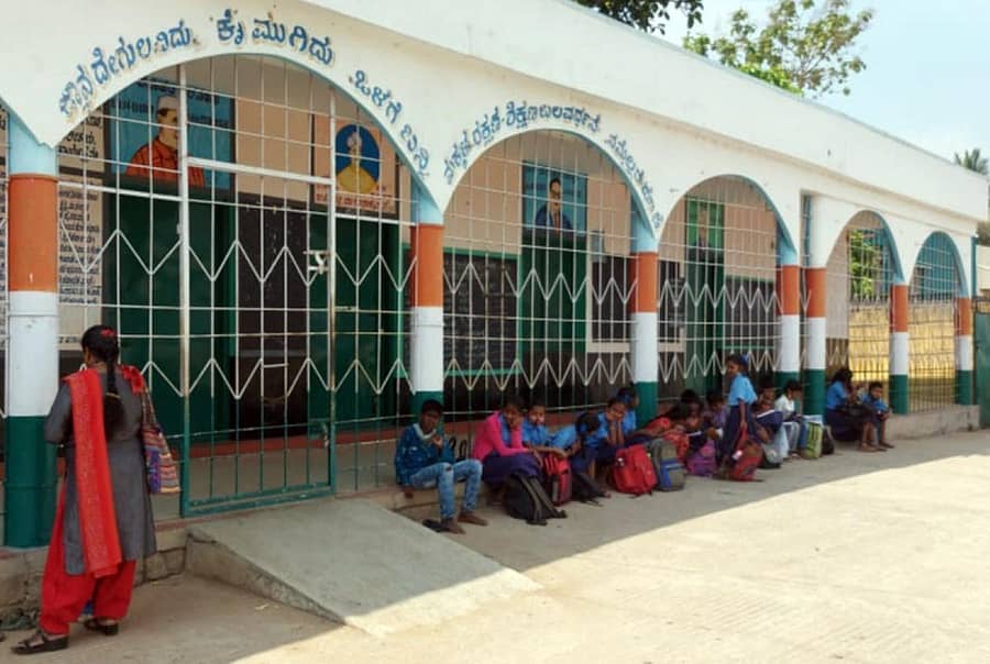 ಶ್ರೀರಂಗಪಟ್ಟಣ ತಾಲ್ಲೂಕಿನ ಮೊಗರಹಳ್ಳಿ ಮಂಟಿ ಗ್ರಾಮದ ಸರ್ಕಾರಿ ಹಿರಿಯ ಪ್ರಾಥಮಿಕ ಶಾಲೆಯ ವಿದ್ಯಾರ್ಥಿಗಳು ಹೊರಗೆ ಕಾದು ಕುಳಿತಿದ್ದರು