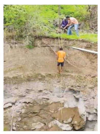 कुत्र्याला वाचविण्यासाठी दोरीच्या साहाय्याने विहिरीत उतरताना हेमंत सूर्यवंशी.
