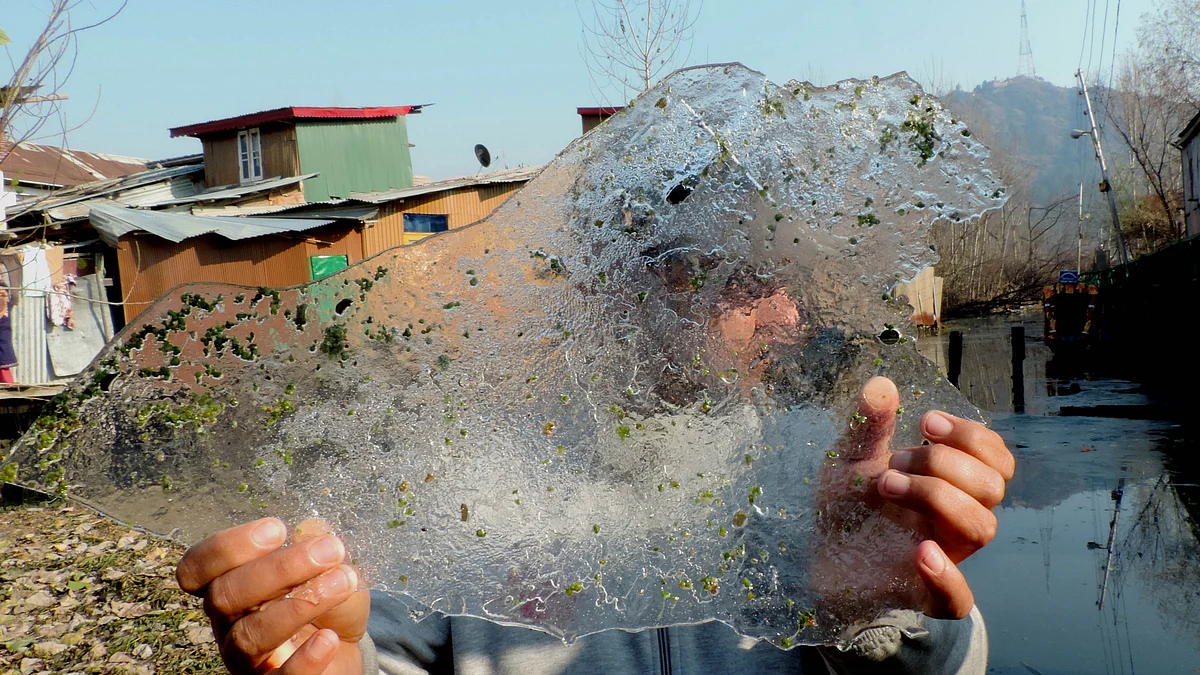 کشمیر: ڈل جھیل میں جمی ہوئی برف دکھاتے ہوئے ایک کشتی سوار / تصویر یو این آئی