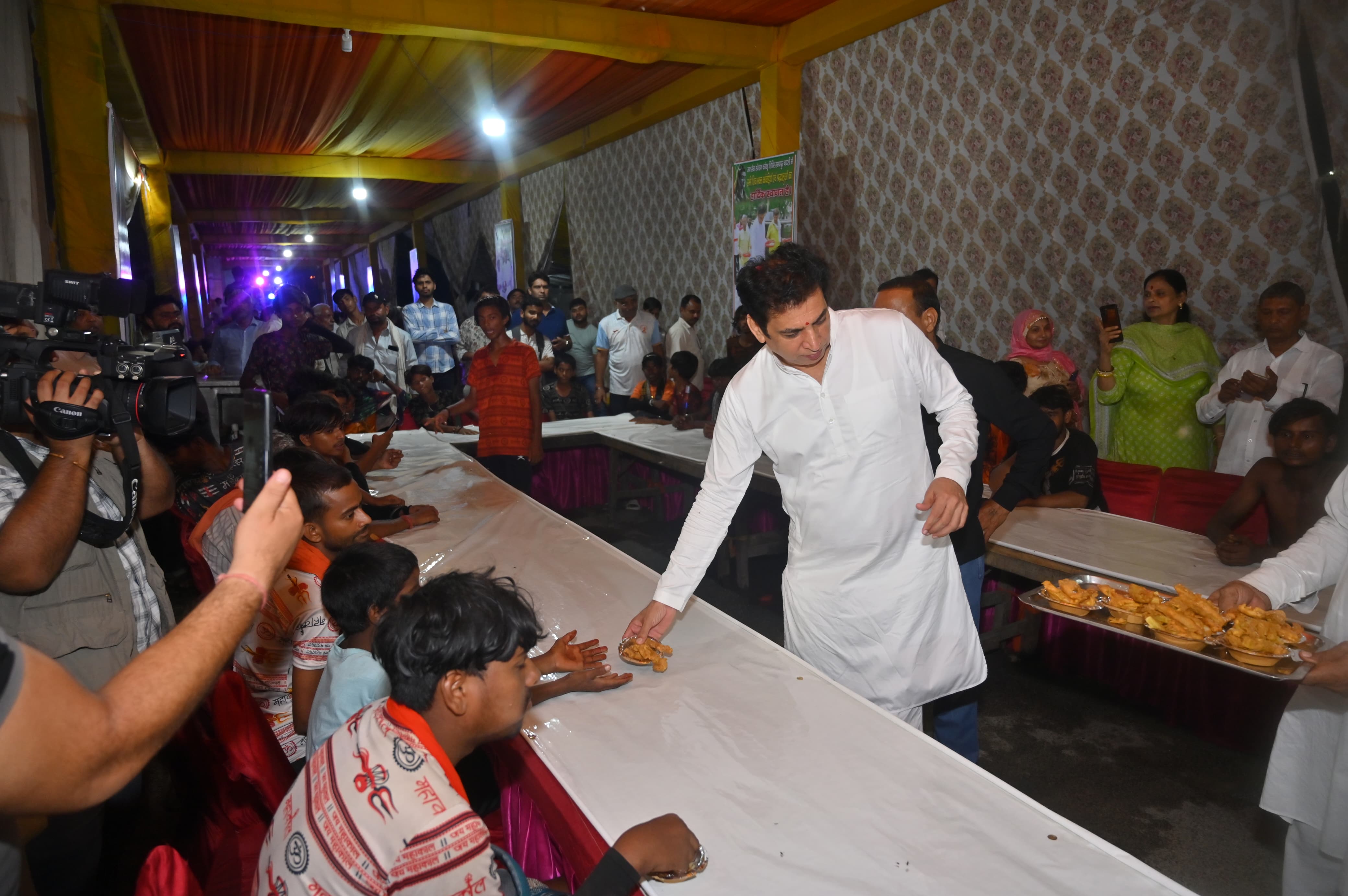 <div class="paragraphs"><p>دیویندر یادو کانوڑ یاتریوں کو مٹھائی تقسیم کرتے ہوئے</p></div>