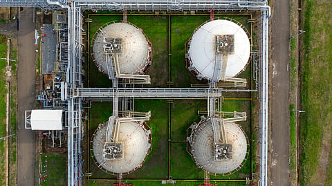 Aerial view of large industrial storage tanks connected through pipelines at an energy processing facility.