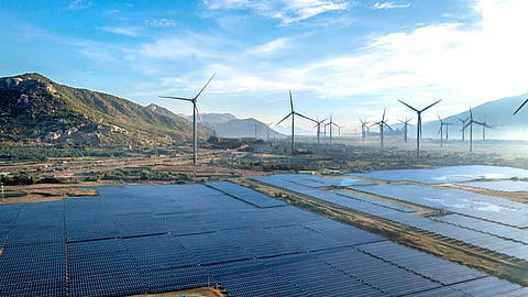 Solar panels and wind turbines operating together at a large renewable energy project site.