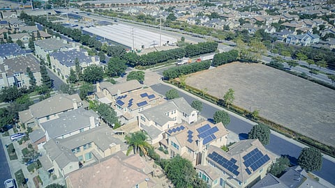 Aerial view of a residential area with multiple homes equipped with rooftop solar panels.