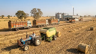 Farmer baling crop residue with trucks transporting biomass to a CBG plant.