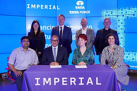 Representatives from Imperial College London and Tata Power pose for a group photograph at a partnership event, seated at a table bearing the Imperial logo in front of a blue backdrop displaying both organisations’ names.