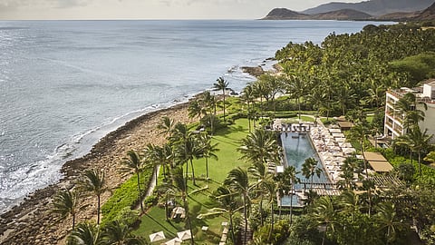 Oceanfront resort with pool and palm trees overlooking Hawaii’s coastline