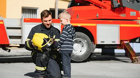Firefighter shows helmet to child during Touch A Truck community event