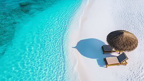 Thatched umbrella and loungers on pristine white sand beach