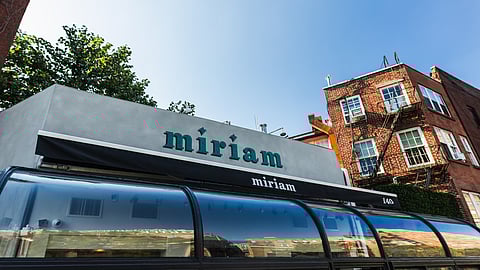 Exterior view of Miriam restaurant with green signage in New York