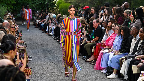 Model in a bold rainbow-striped dress walks the Libertine SS26 runway