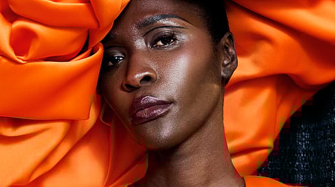 Model in bold orange look with radiant skin at Christian Siriano NYFW 2026