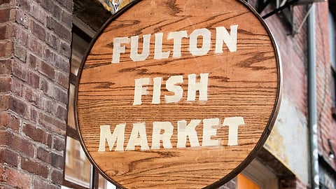 Wooden Fulton Fish Market sign hanging outside a building in the Seaport