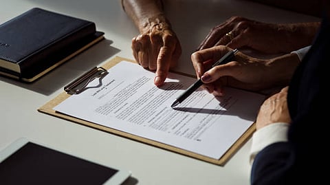 Hands review and sign a contract on a clipboard in office light