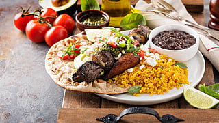 Beef kebab with rice, beans and fried plantains