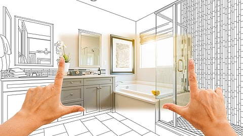Hands framing a bathroom design concept mixing blueprint and reality