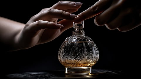 Hands spraying perfume from an ornate glass bottle