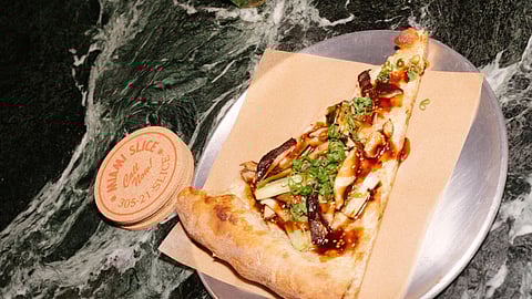 Slice of pizza topped with scallions and mushrooms