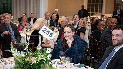 Woman raising auction paddle at gala dinner event