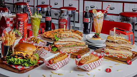 Hot dogs, milkshakes, and sandwiches on a retro table