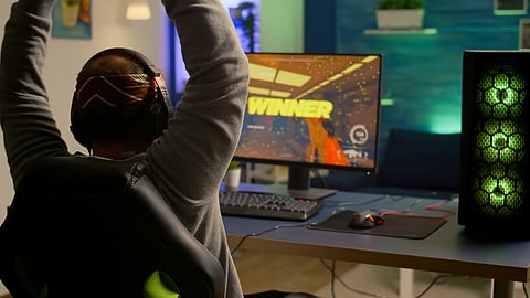 Gamer celebrating a win while playing a PC game in a colorful setup