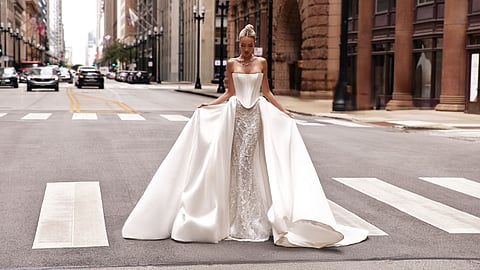 Bride in a strapless satin wedding gown posing on a city street