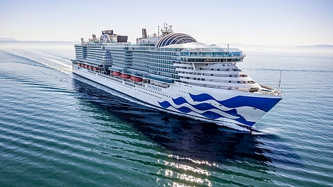 Star Princess cruise ship gliding across calm blue waters at sunrise.