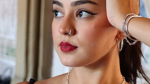 Arisa Kumar wearing diamond jewelry and red lipstick, gazing thoughtfully