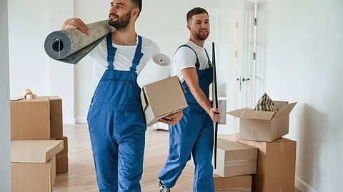 Two professional movers carrying boxes and items in a Boston apartment