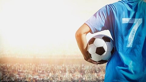 Soccer player wearing blue jersey number seven holding a ball in a stadium