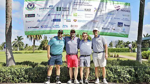 Golfers pose under sponsor banner at Heartbeats for PATCHES tournament